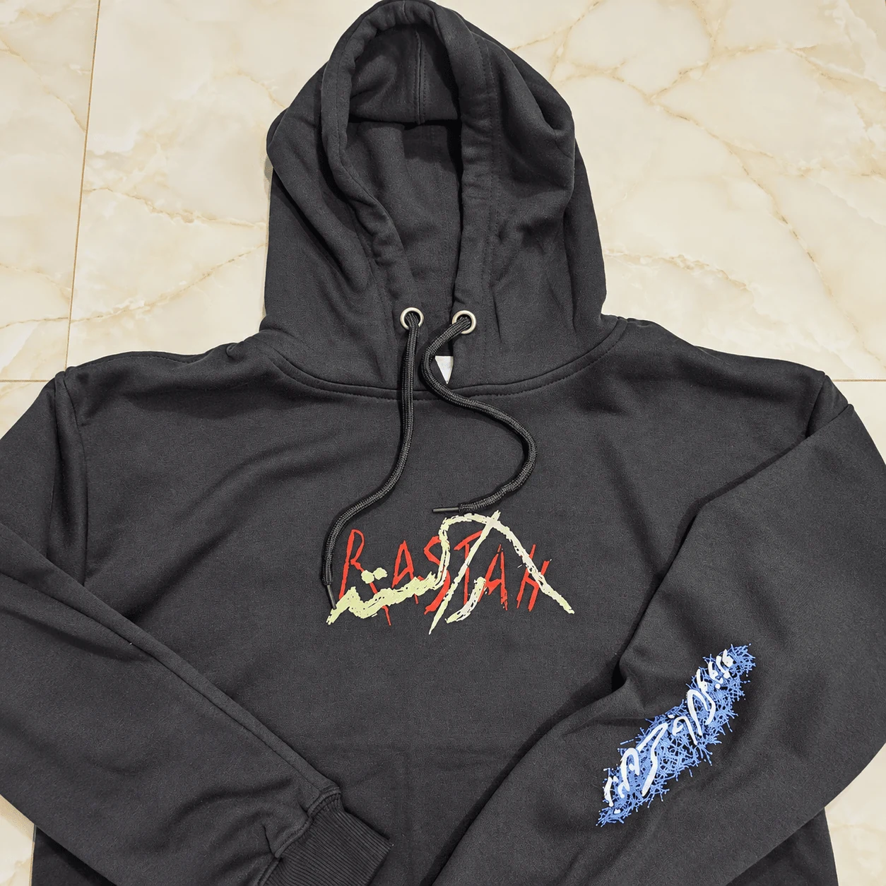Black heavyweight streetwear hoodie with RASTAA chest print and flame sleeve detail